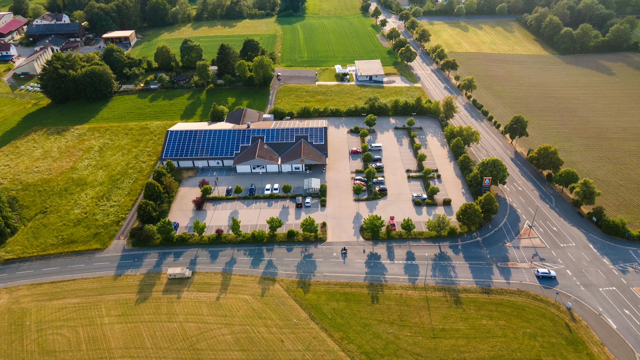 Aerial shot of a solar-powered building and parking lot surrounded by fields in Rehau, Germany.