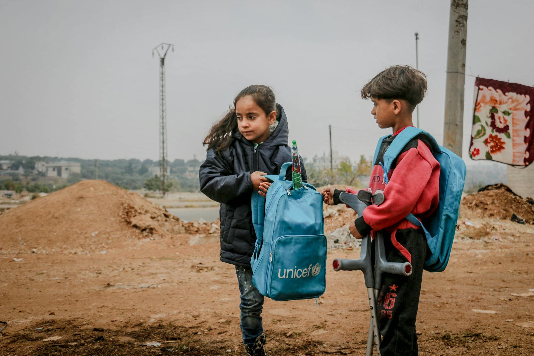 Poor ethnic children with crutches talking in rural areas under gloomy gray sky in daytime